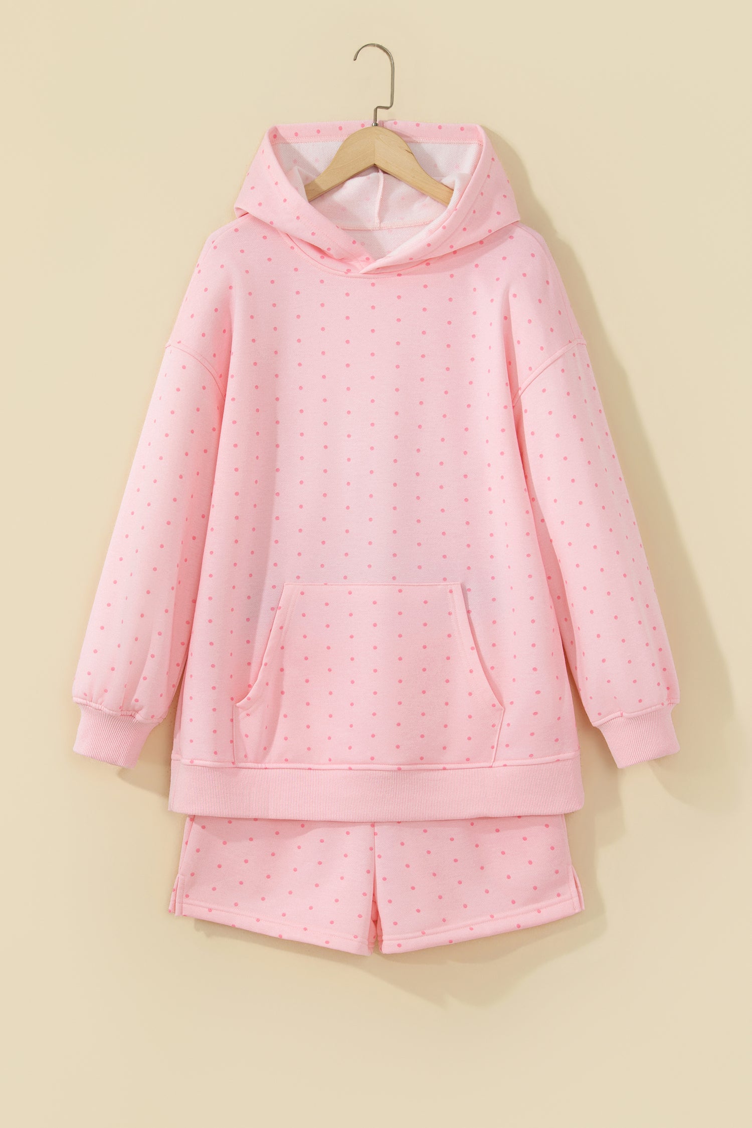 Pink polka dot hoodie and shorts set on a hanger, front view