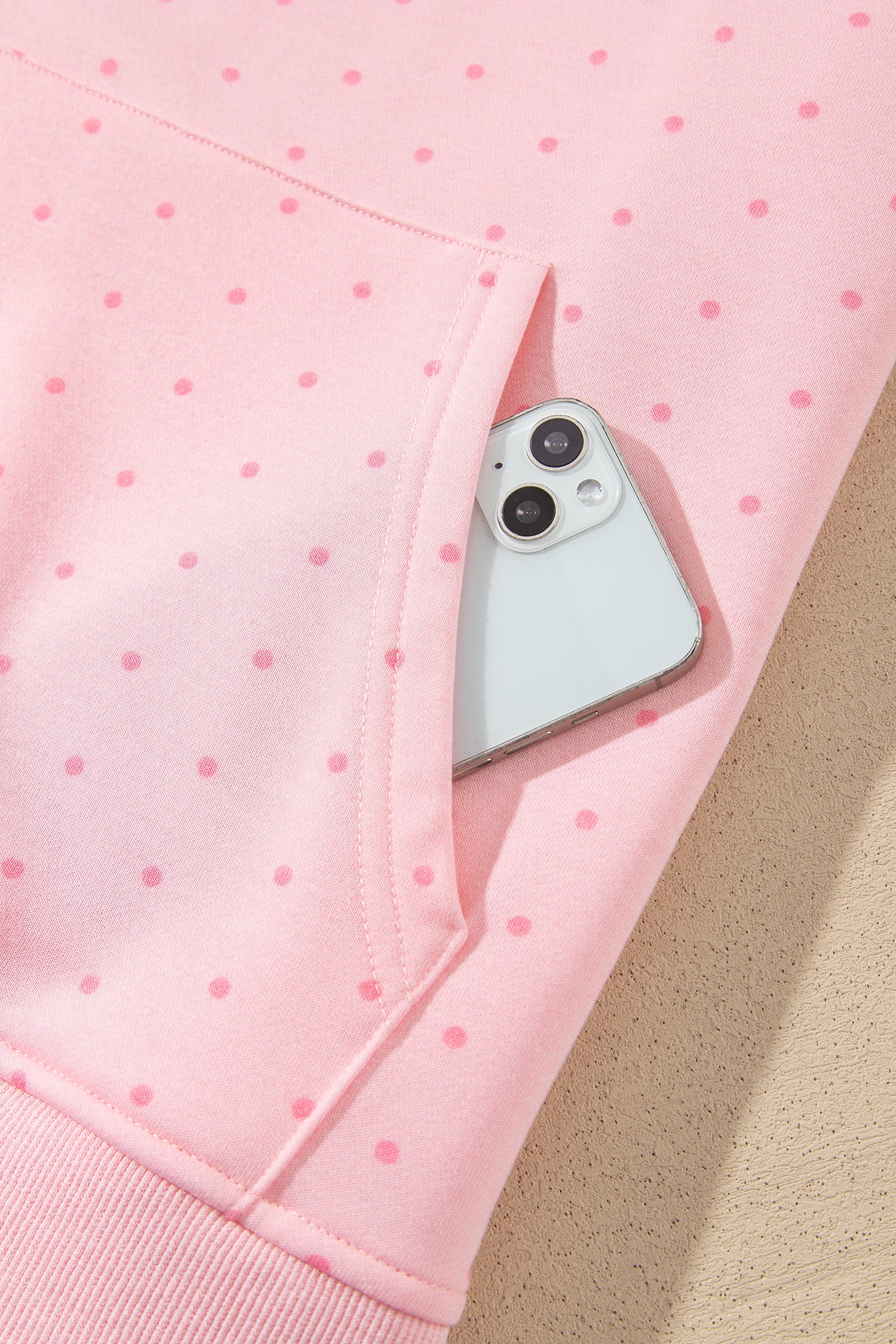 Pink polka dot hoodie kangaroo pocket holding a phone