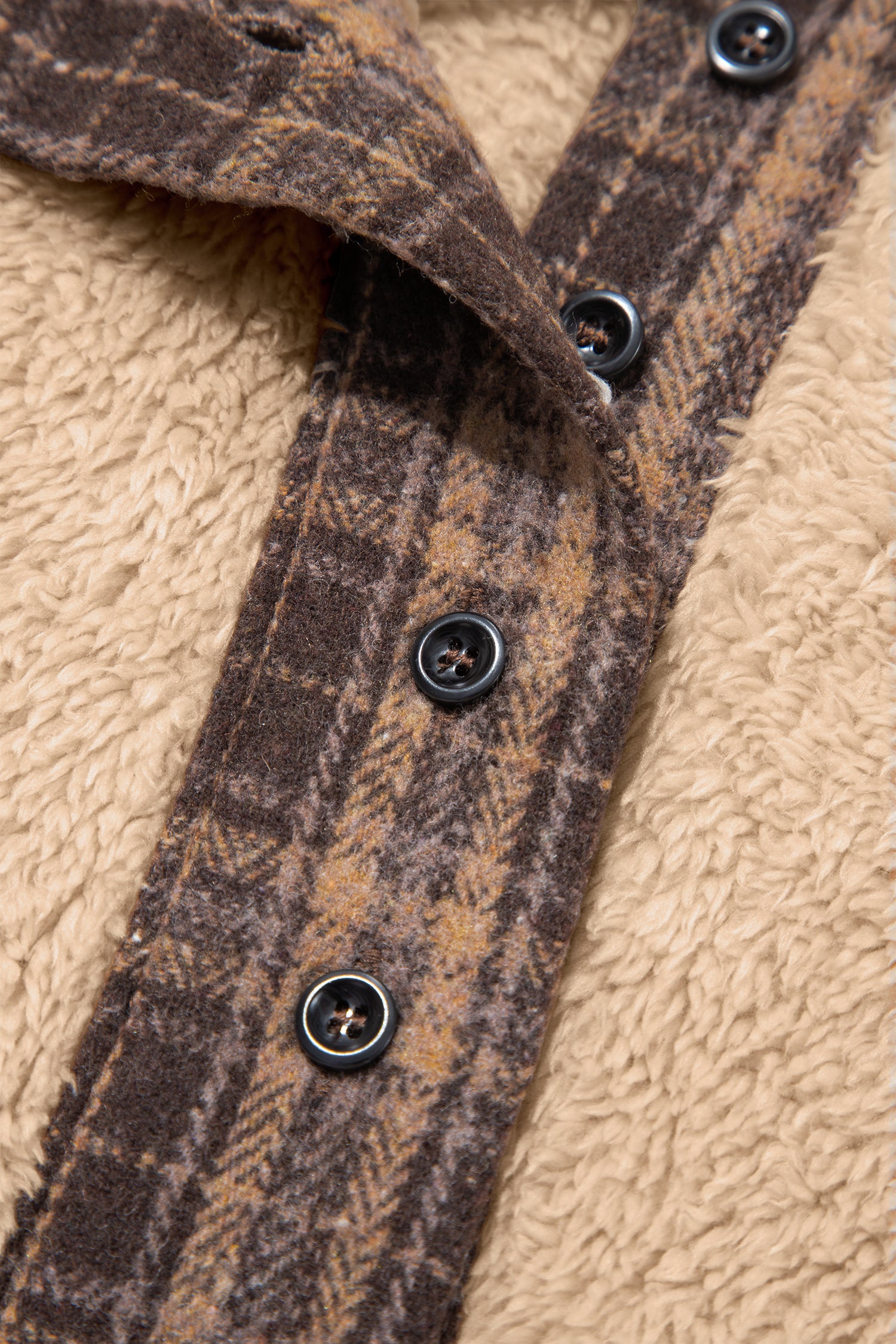 Close-up of brown plaid button placket on beige sherpa fleece