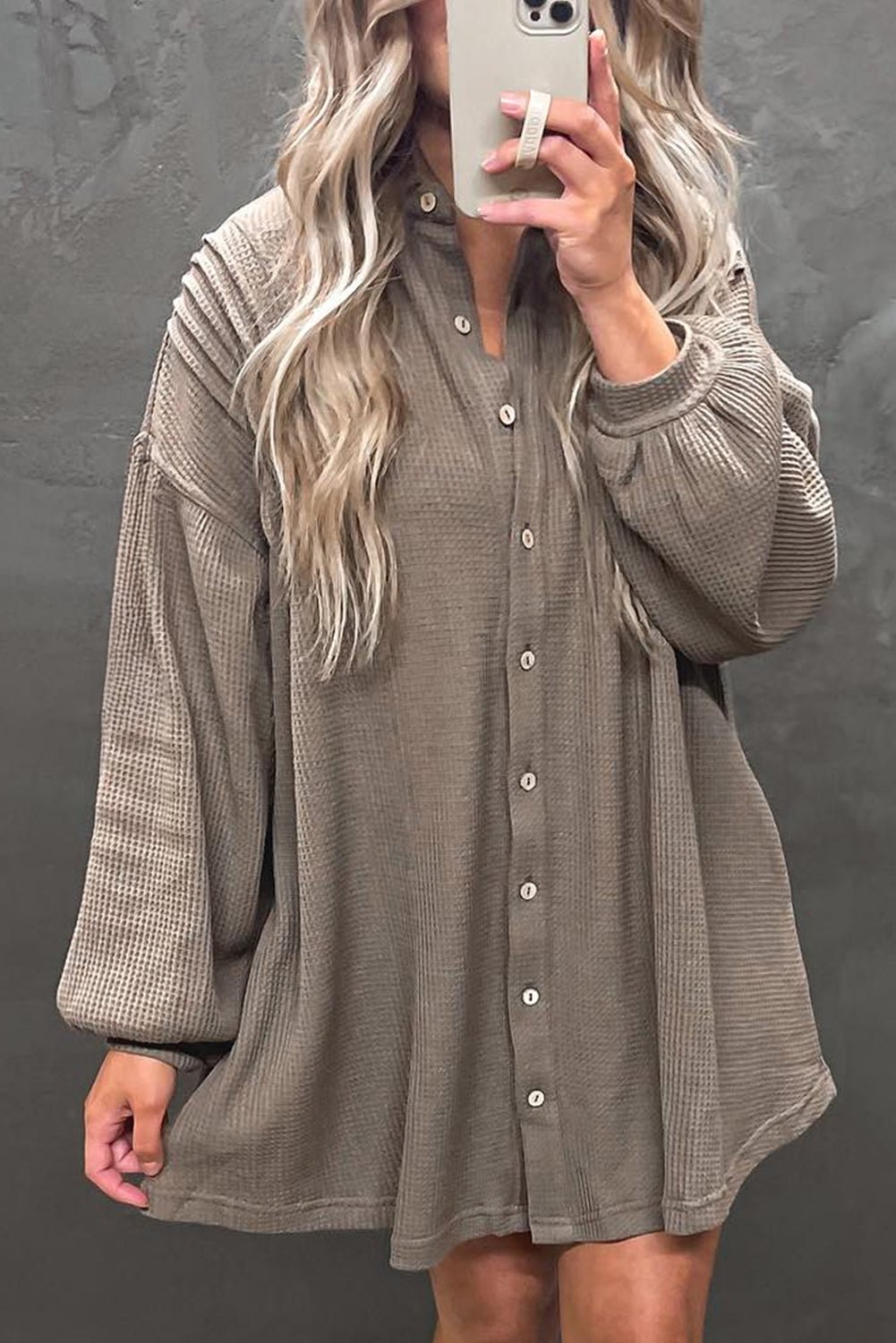 Person wearing a long-sleeve button-up dress with a plaid pattern on a plain background