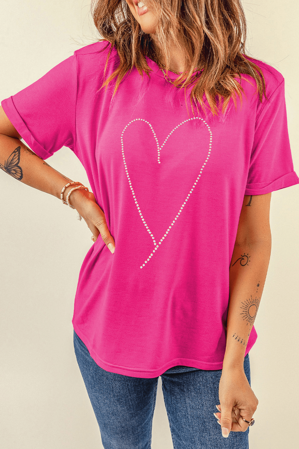 Person wearing a bright pink t-shirt with a heart design on a beige background