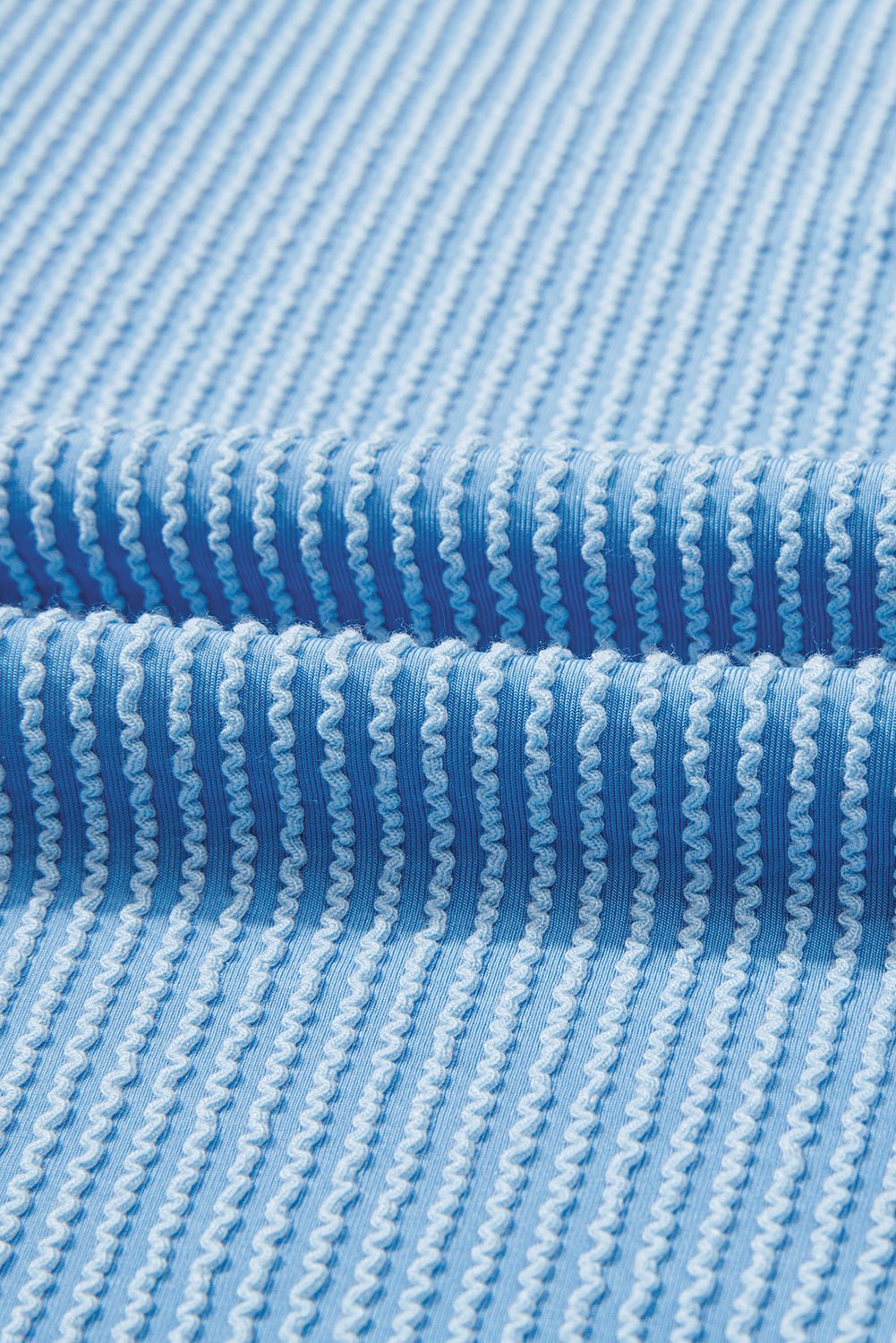 Close-up of blue textured fabric with horizontal stripes.