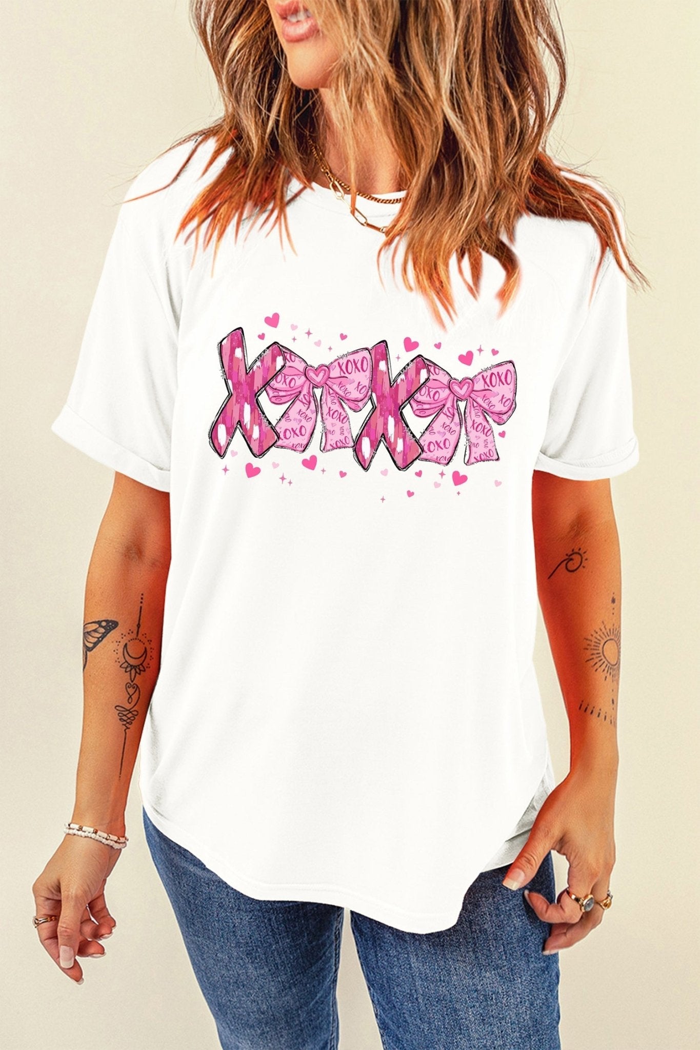 Person wearing a white t-shirt with pink graphics and text on a beige background