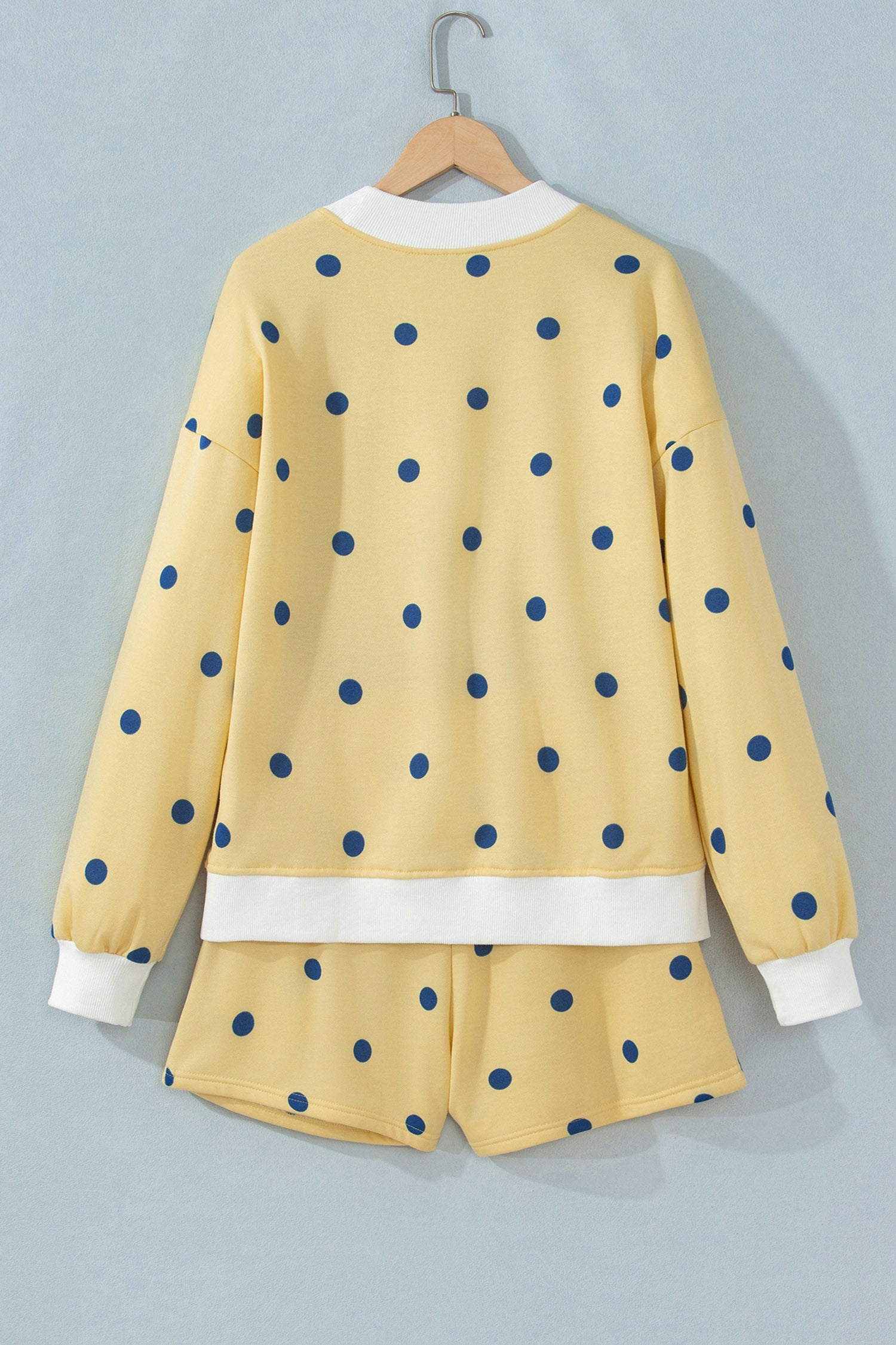 Yellow polka dot top and shorts set on hanger, back view