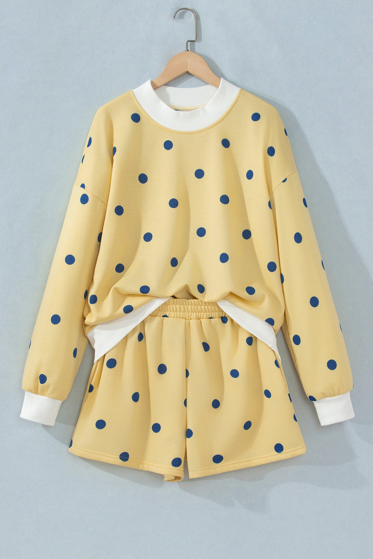 Yellow polka dot top and shorts set on hanger, front view