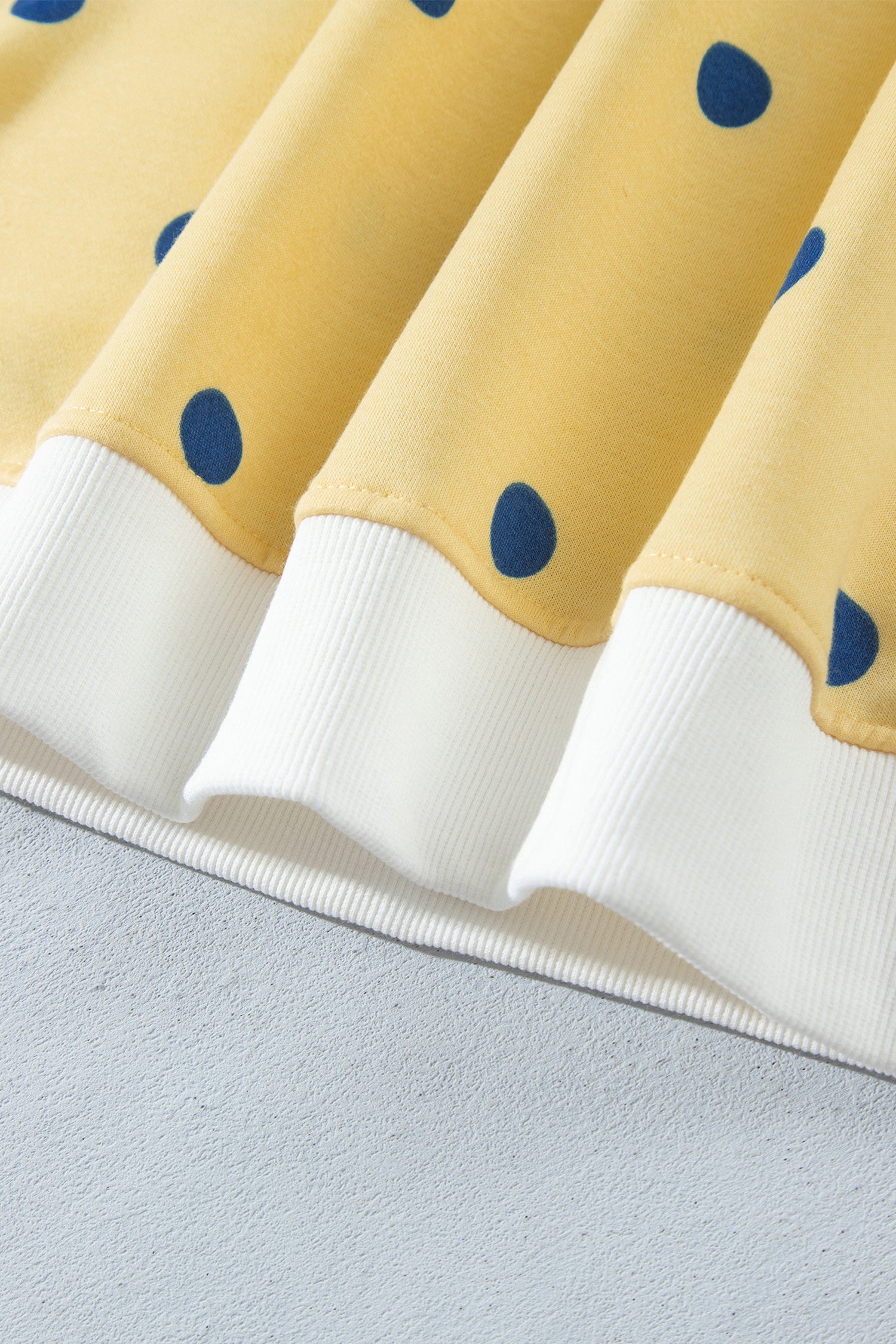 White ribbed hem band on yellow polka dot top, close-up