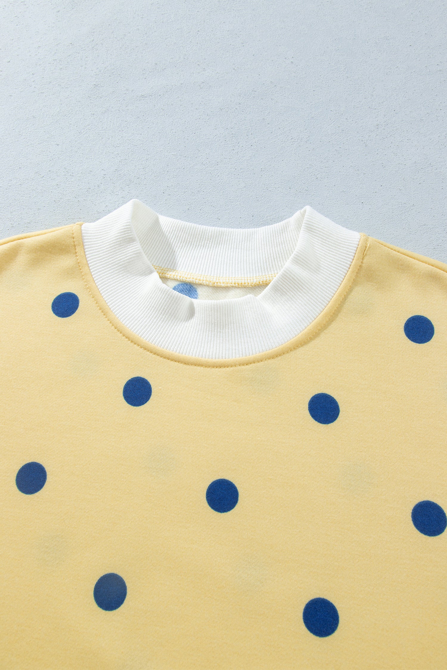 Contrast white ribbed crew neckline on yellow polka dot top