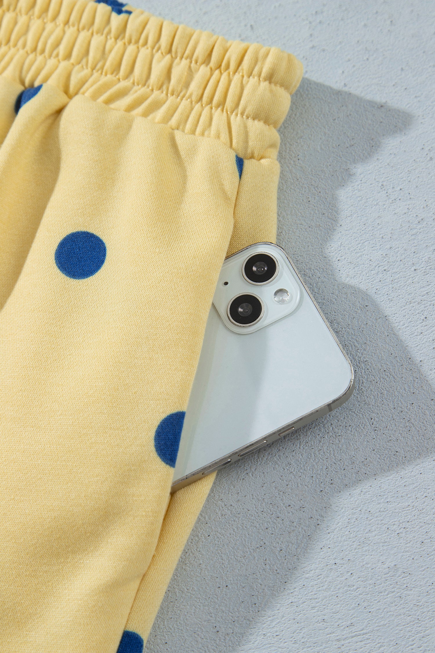 Side pocket holding a phone on yellow polka dot shorts