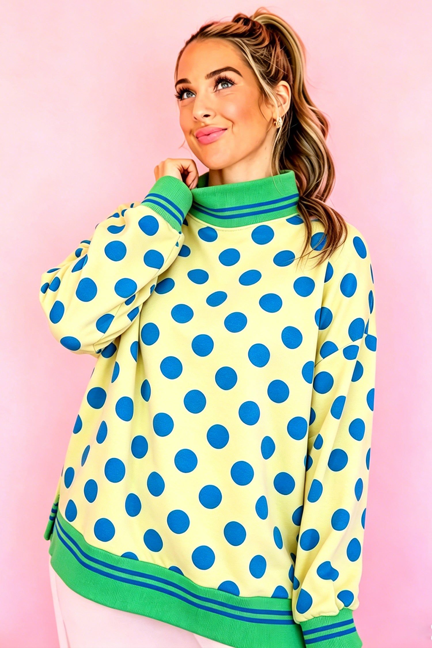 Woman in yellow oversized sweatshirt with blue polka dots and green ribbed trim