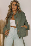 Woman wearing an olive green jacket and light blue jeans against a neutral background