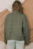 Person wearing a green quilted jacket with a neutral background